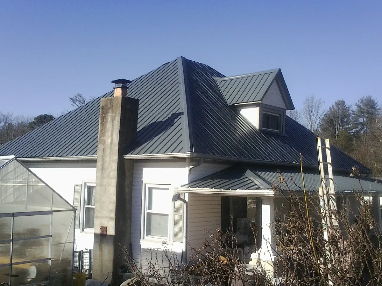 Dark blue standing seam metal roof on a white farmhouse with dormer — Slate & Tile Roof Repair by Roofing Brothers in Grantville