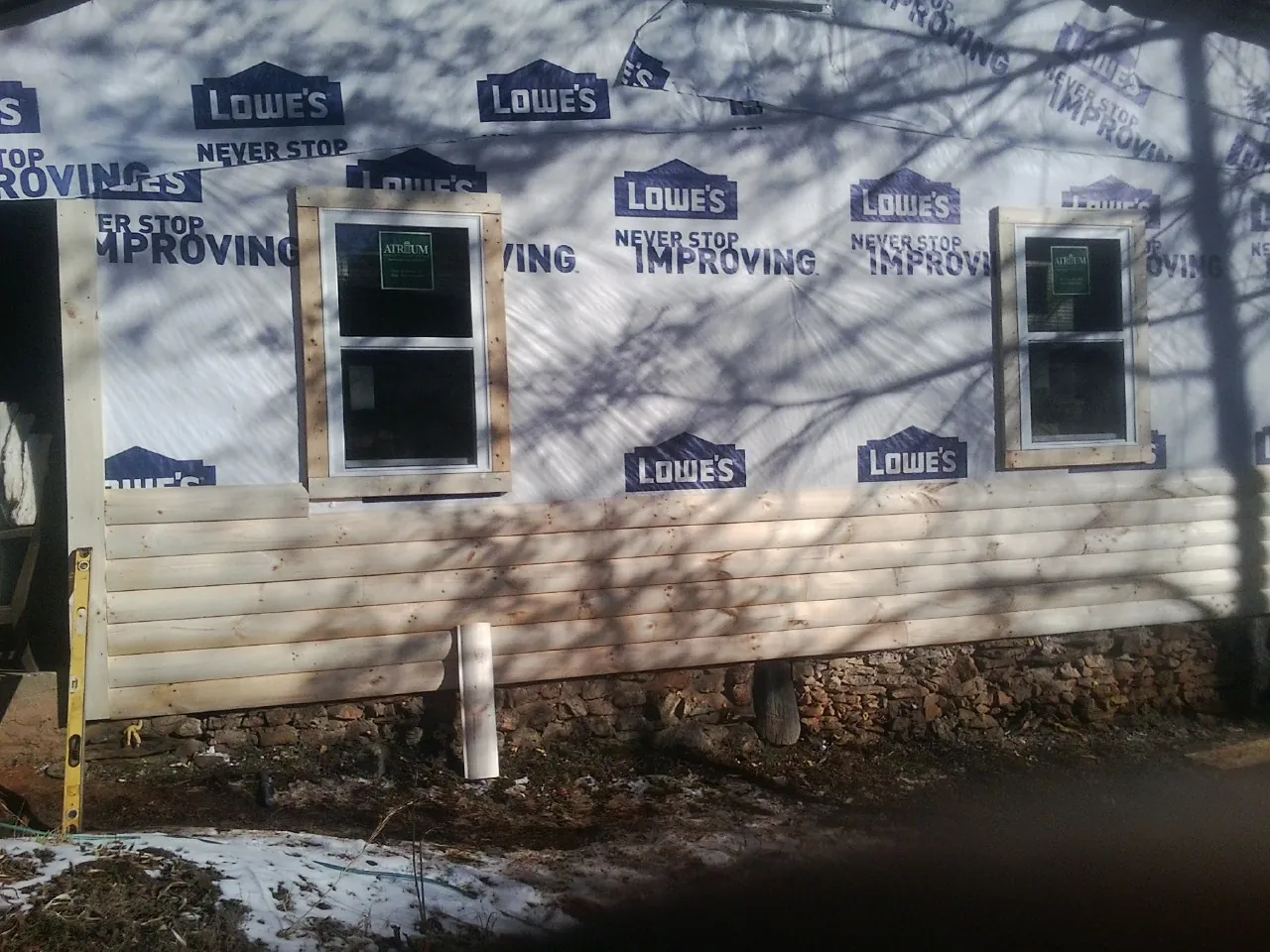 House wrap and new log siding going up on an exterior wall in Grantville