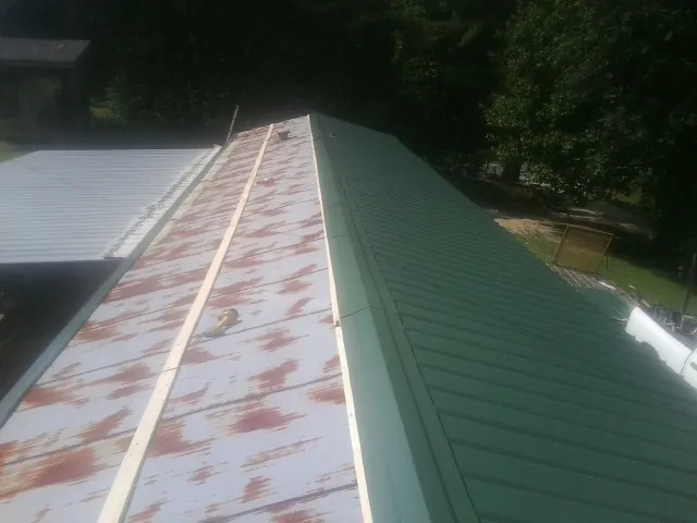 Old rusted panels beside newly installed green metal roofing — Wind Damage Roof Repair by Roofing Brothers in Grantville