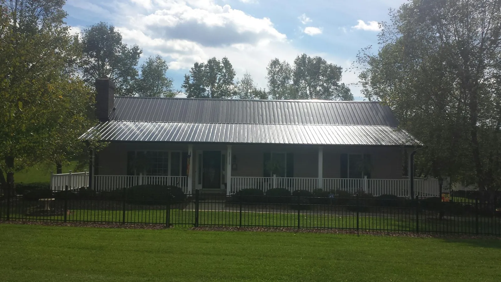 Gray metal roof on a brick ranch with a full width front porch — Gutter Guard Installation work by our crew in Grantville